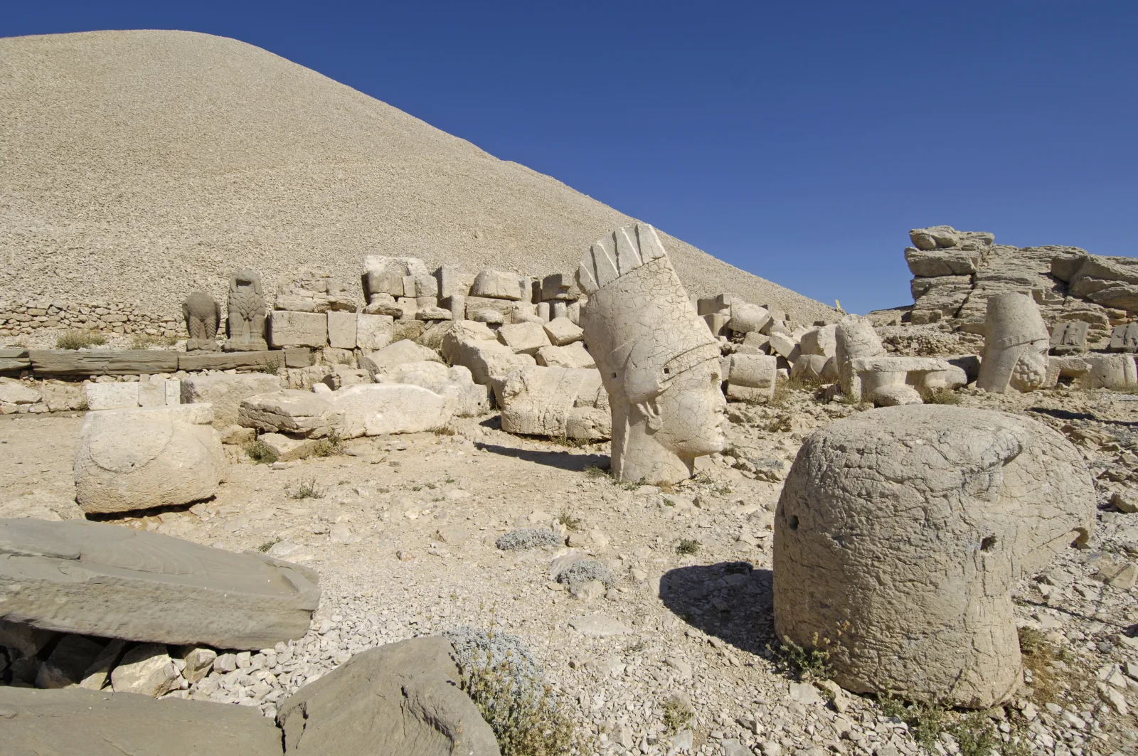 Nemrut Dağı'nın batı terasında sıra halinde duran dev heykel başları, arkada tümülüs