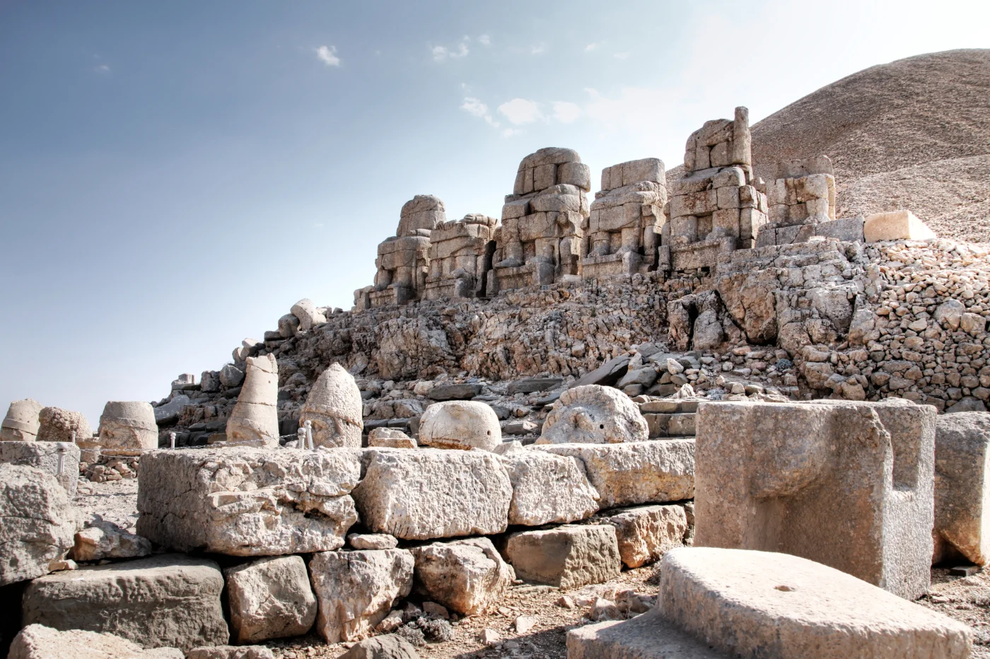 Nemrut Dağı doğu terasındaki oturan heykellerin gövdeleri ve kesik başları, arkada Toroslar manzarası