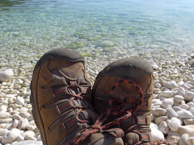 Likya Yolu’nda çakıllı sahilde dinlenen tozlu trekking ayakkabıları