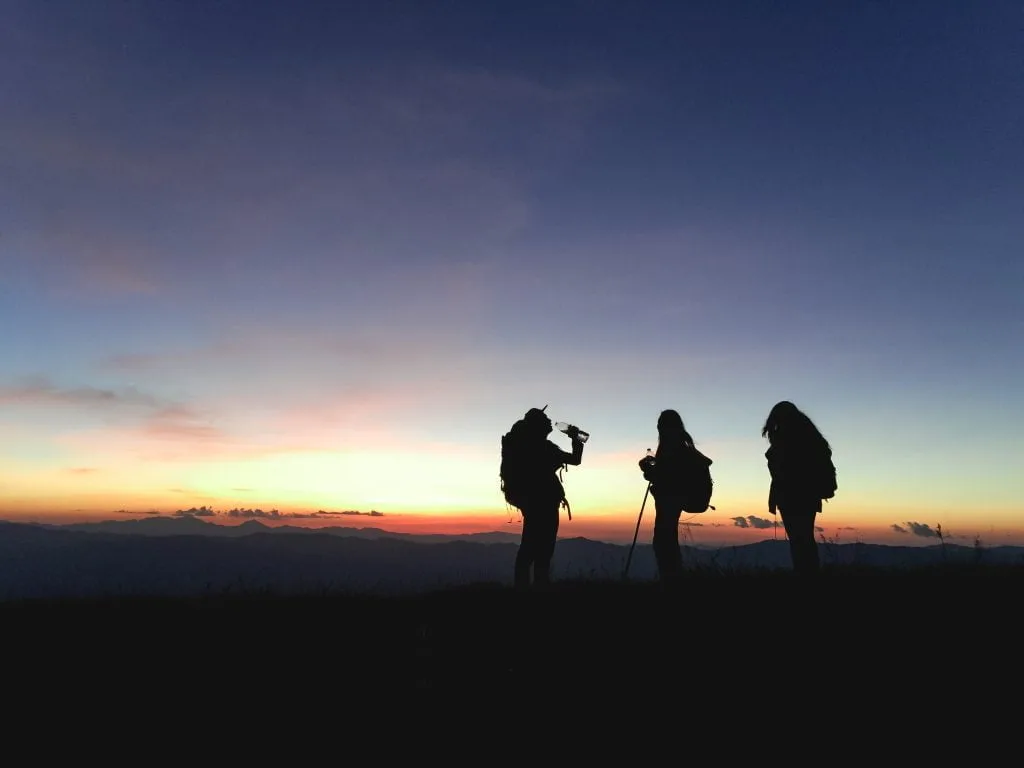 Gün batımında mola veren sırt çantalı trekking grubu
